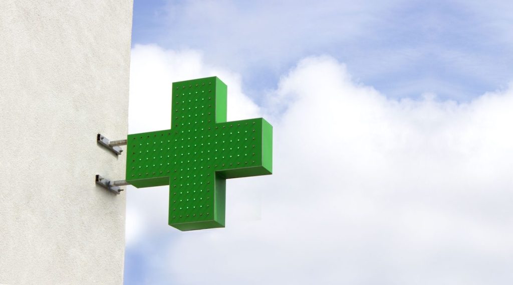 Ein leuchtend grünes Kreuz an einer Hauswand, das typische Erkennungsmerkmal für eine Apotheke (Ljekarna) in Kroatien auf der Insel Krk.