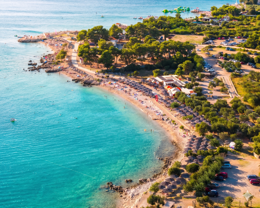 Gepflegte Rasenfläche mit Olivenbäumen und Sonnenliegen an der Medane Beach Bar in Punat auf Krk.