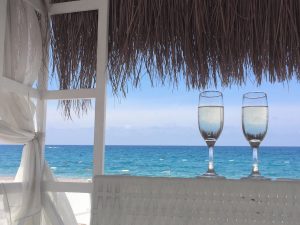 Zwei Gläser am sonnigen Strand mit Meerblick. Text: "#URLAUBAUFKRK" und Buttons für Instagram, Facebook und WhatsApp.