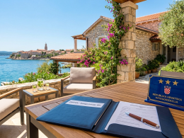 Offizielles blaues Schild mit drei Sternen zur Kategorisierung und Antragsdokumente auf einem Tisch auf einer Terrasse mit Meerblick auf der Insel Krk.