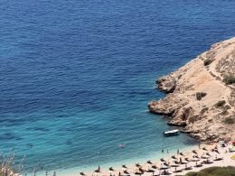 Blick von oben auf den Oprna Beach bei Stara Baška auf der Insel Krk mit Badegästen und Booten im türkisen Wasser.