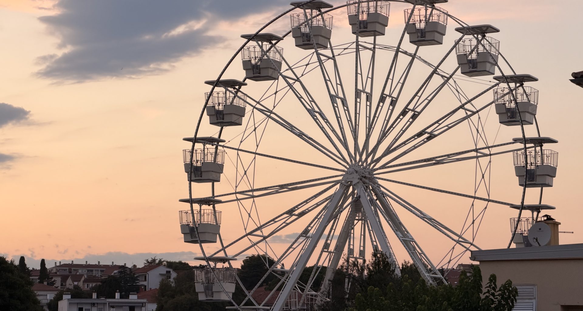 Das beleuchtete Riesenrad in der Stadt Krk bei Nacht mit Blick auf den Hafen.