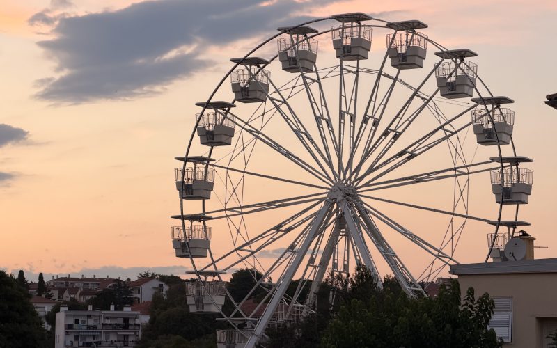 Das beleuchtete Riesenrad in der Stadt Krk bei Nacht mit Blick auf den Hafen.